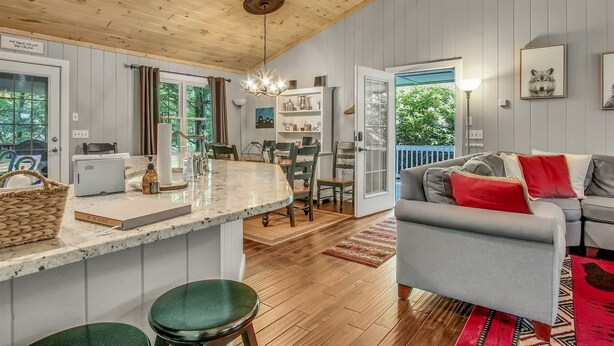 A spacious living area with a grey sofa, a kitchen with wooden cabinets, and a dining area with a table and chairs. - Just the Right Size. Exactly Enough | Highlands Haven (Highlands)