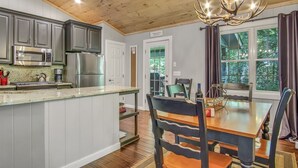 A kitchen with a central island, stainless steel appliances, and a chandelier. - Just the Right Size. Exactly Enough | Highlands Haven (Highlands)