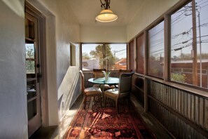 Un pasillo con un área de comedor que incluye una mesa, sillas, una lámpara colgante y ventanas grandes con vistas al exterior.