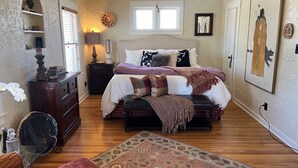 Un dormitorio con cama, mesitas de noche, cómoda, alfombra y ventilador de techo.