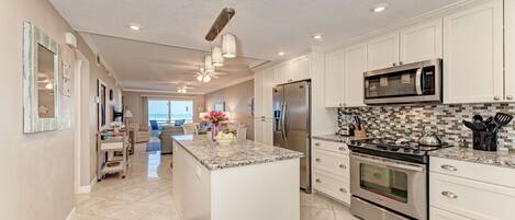 A modern kitchen with white cabinets, stainless steel appliances, and a large island.