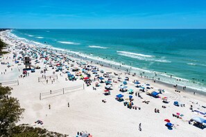 A beach with numerous umbrellas and people.