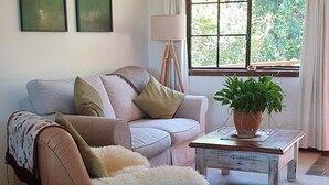 A living room with a sofa, a coffee table, and a potted plant.