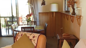 A cozy living room with a sofa, a chair, a table, and a window with curtains.