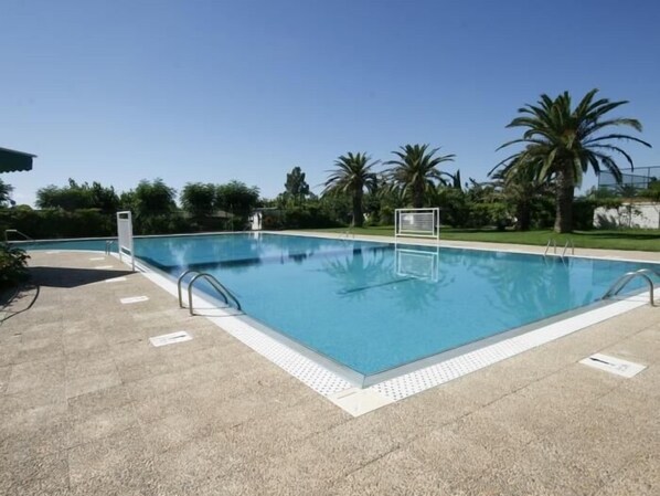 Ein rechteckiger Swimmingpool mit glasklar blauem Wasser, umgeben von einer gefliesten Liegefläche.