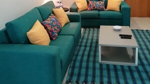 A living room with two green sofas, colorful pillows, a small table, and a lamp. - Hot Water House 2 (Furnas)