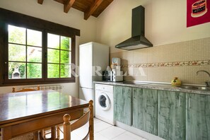 Een koelkast, een magnetron, kookgerei, borden en bestek, eettafels