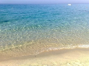 A clear view of a sandy beach with shallow water and a boat in the distance. - Apartment in Three-Family Villa with Large Balcony with Sea View "OPUNTIA"    (Capo Vaticano)
