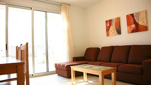Un salon comprenant un canapé, une table basse en bois et une table à manger avec des chaises.