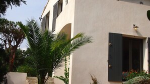 Ein Gebäude mit einer beigefarbenen Fassade, dunklen Fensterläden und einer Tür mit kleinem Fenster.