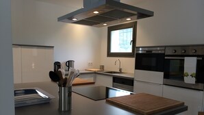 Eine moderne Küche mit Edelstahlgeräten, einem Holzer Schneidebrett und einem Besteckhalter.