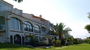 A multi-story building with balconies, arched windows, and a well-maintained lawn.