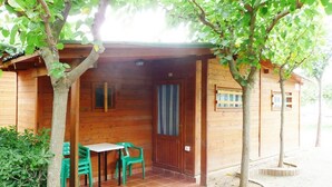 A wooden cabin with a covered patio, a door, and a window.