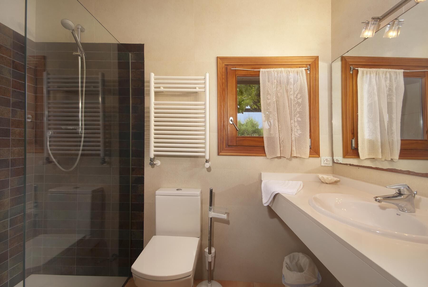 A bathroom with a glass-enclosed shower, a toilet, a sink, and a towel rack.