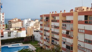 Un edificio residencial de varios pisos con balcones, piscina y vistas al mar.