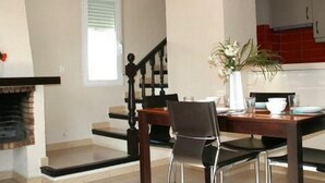A dining area with a wooden table and chairs, a vase with flowers, and a kitchen in the background. - APCOSTAS Retiro Park - DENIA / One Bedroom (Denia)
