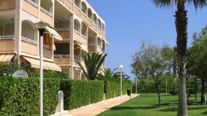 Un hôtel à plusieurs étages doté de balcons, d’une pelouse bien entretenue et de palmiers.