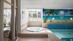 Ett spaområde med ett bubbelbad, en väggmålning som föreställer en strandscen och en pool.