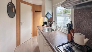 Een kleine keuken met een roestvrijstalen spoelbak, een waterkoker en een gasfornuis.