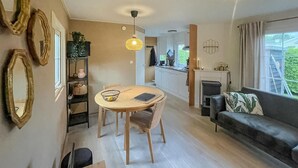 Een moderne woonkamer met een bank, een eettafel met stoelen, een keuken en een open haard.