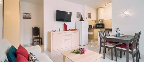 A modern living room with a sofa, a coffee table, and a dining area with chairs and a table.