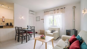 A living room with a sofa, a coffee table, and a dining area with chairs and a table. - Apartment Al Gharb (Carvoeiro)