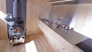 A modern kitchen with a wood-burning stove, stainless steel sink, and wooden walls. - Experience the special (Nußdorf/Debant)