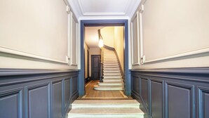 Eine imposante Treppe mit Teppichboden und einer Leuchte am oberen Ende.
