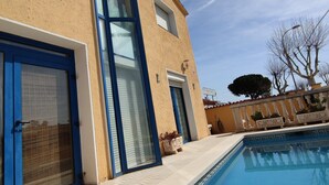 A building with a swimming pool, a blue door, and a window with blinds.