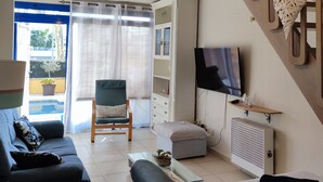A living room with a sofa, a chair, a TV, a bookshelf, and a decorative wall piece.