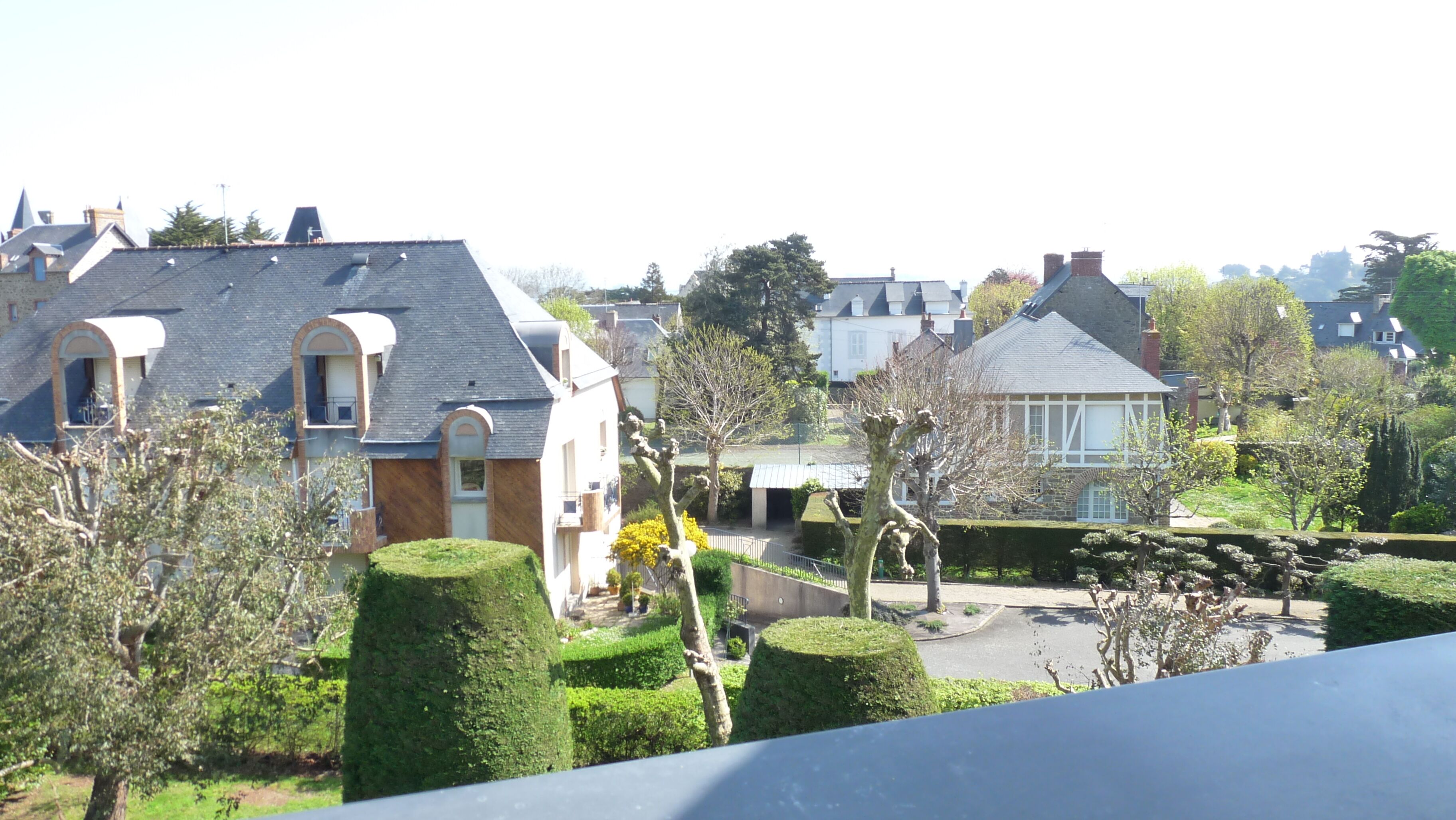 Un quartier résidentiel avec des maisons, des haies bien entretenues et un ciel dégagé.