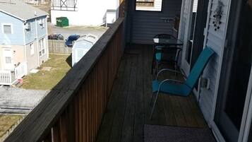 Terraza de madera con dos sillas y una mesa, con vista a un barrio residencial.
