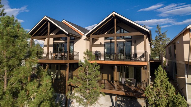 A modern multi-story building with balconies, large windows, and a mountainous backdrop. - Modernist Mountain View Retreat in Old Mill!! Hot Tub!!!  Pool Table!!! (Bend)