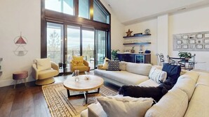 A spacious living room with a large window, a round coffee table, and a sofa with multiple cushions. - Modernist Mountain View Retreat in Old Mill!! Hot Tub!!!  Pool Table!!! (Bend)
