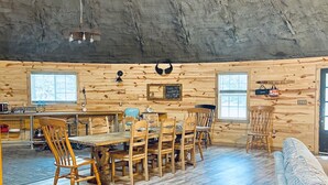 Un interior rústico de madera con zona de comedor, sillas de madera, una mesa y un sofá.