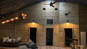 Un interior acogedor de madera con techo inclinado, ventilador de techo y zona de estar con sofá y sillones.