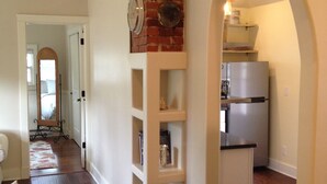 A spacious kitchen with a brick wall, white cabinetry, and a stainless steel refrigerator. - Charming Cheyenne Cañon Cottage, Steps To The Broadmoor & Seven Falls! (Colorado Springs)