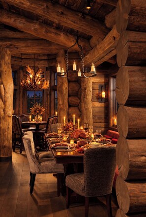 A rustic dining room with a wooden table set for a meal, surrounded by upholstered chairs. - Breathtaking Mountainside Alpine Retreat, Five Bedrooms, Warm & Opulent, Cinema! (Vail)
