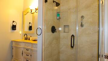 Une salle de bain comprenant un meuble-lavabo, un miroir, une douche avec une porte en verre et un porte-serviettes.