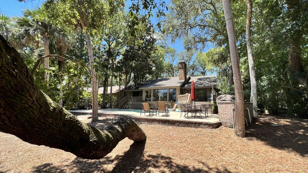 Una casa con un porche techado, mobiliario exterior y una piscina.
