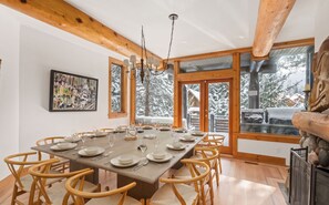 A dining area with a large wooden table set for six, surrounded by wicker chairs.
