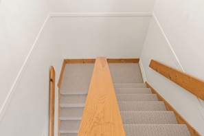 A staircase with wooden handrails and carpeted steps.
