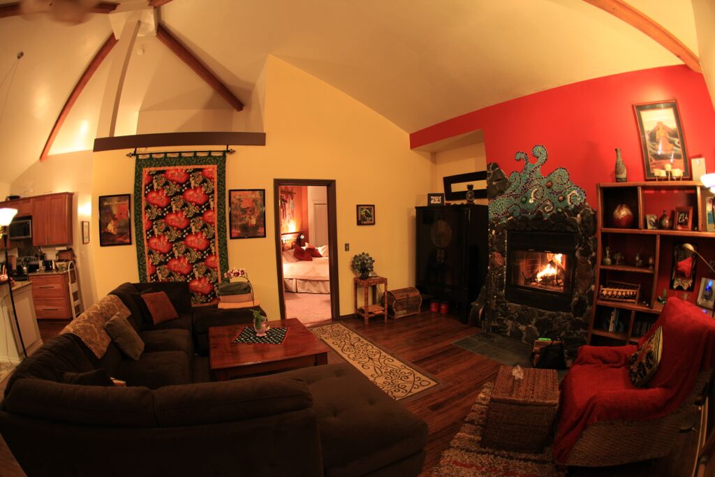 A cozy living room with a fireplace, a sofa, a red armchair, and a bookshelf.
