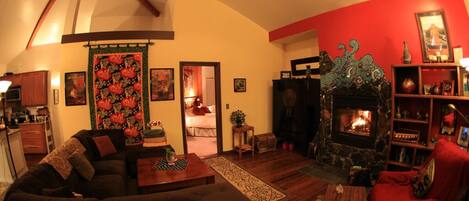 A cozy living room with a fireplace, a sofa, a red armchair, and a bookshelf.