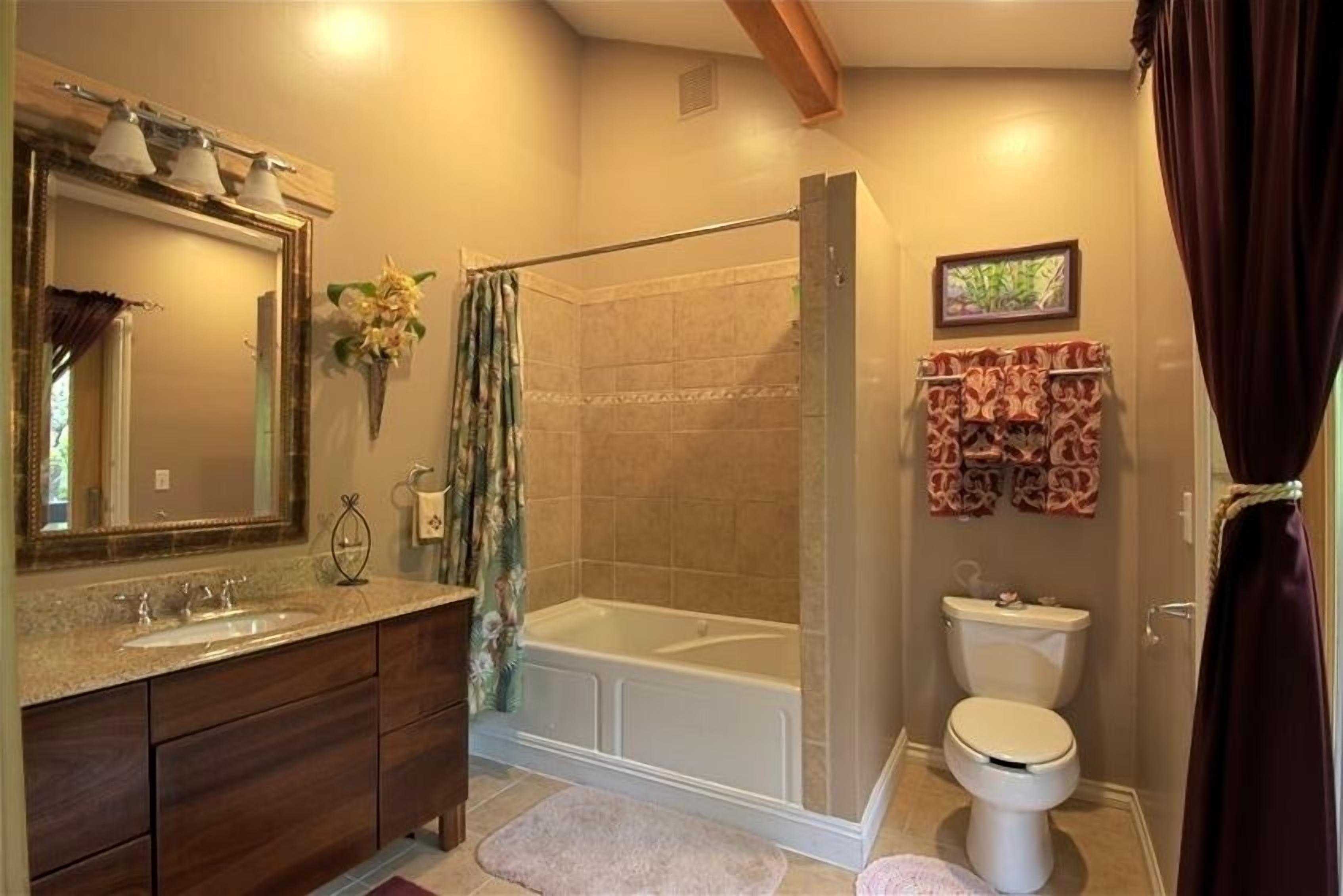 A bathroom with a bathtub, toilet, vanity with a sink, and a shower curtain.