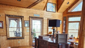 A wooden cabin interior with a wooden desk, a chair, and a window with a view of trees. - 3 King Suites! Great Views! Outdoor Fireplace! Paved Roads! Pets! Access Ramp! (Blue Ridge)