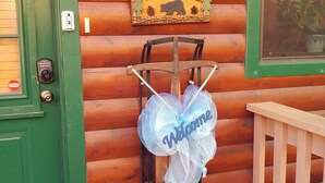 A wooden cabin with a green door, a welcome sign, a lantern, and a bench. - Two King Suites! Endless View!  Close to Town. All paved roads. Pet Friendly. (Blue Ridge)