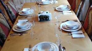 A wooden dining table set with white plates, glasses, and cutlery, surrounded by patterned chairs. - Two King Suites! Endless View!  Close to Town. All paved roads. Pet Friendly. (Blue Ridge)