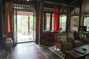 An open doorway leading to an outdoor area with a table and chairs, a sofa, and a bookshelf with books. - Maison Haily (Hanoi)