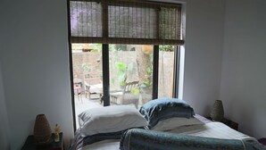Un dormitorio con cama, mesita de noche, lámpara y ventana con persianas.